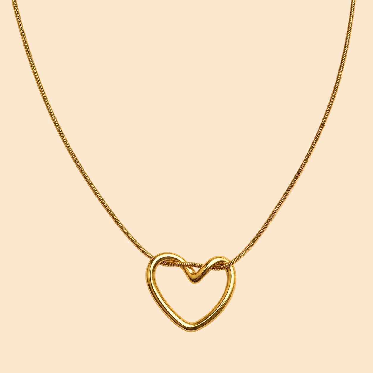 Gold heart-shaped necklace on a beige background