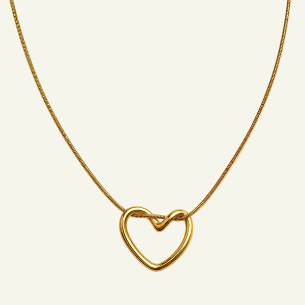Gold heart-shaped necklace on a beige background