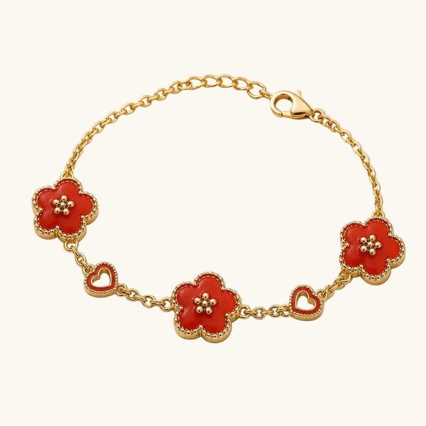 Gold bracelet with red enamel clover flower charms and open heart charms on cable chain