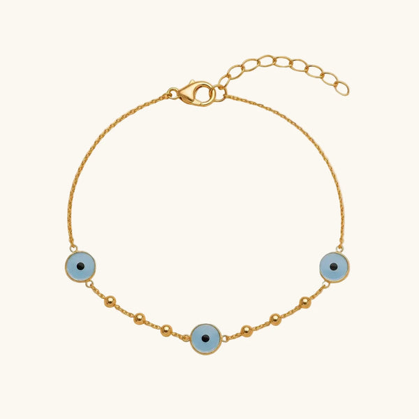 A delicate gold chain bracelet featuring three light blue evil eye charms with black centers